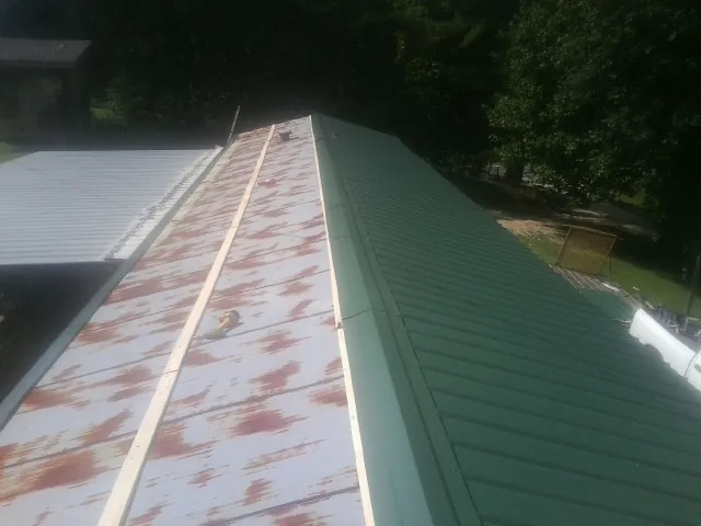 Old rusted panels beside newly installed green metal roofing — Wind Damage Roof Repair by Roofing Brothers in Wickliffe
