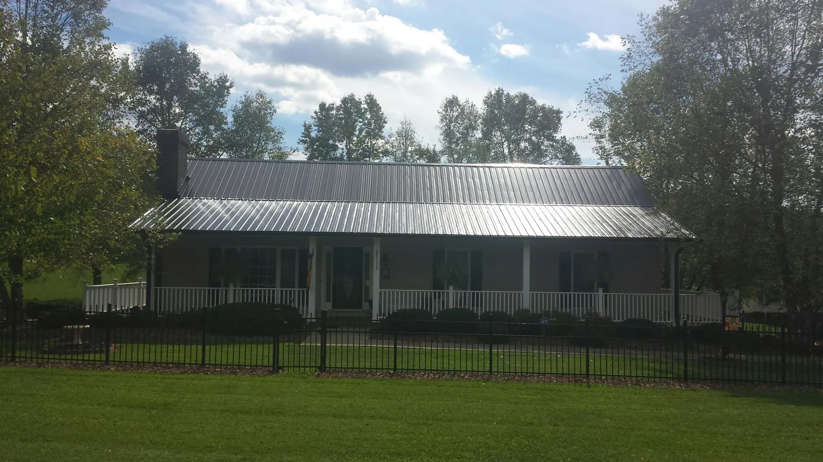 Gray metal roof on a brick ranch with a full width front porch — Gutter Guard Installation work by our crew in Wickliffe