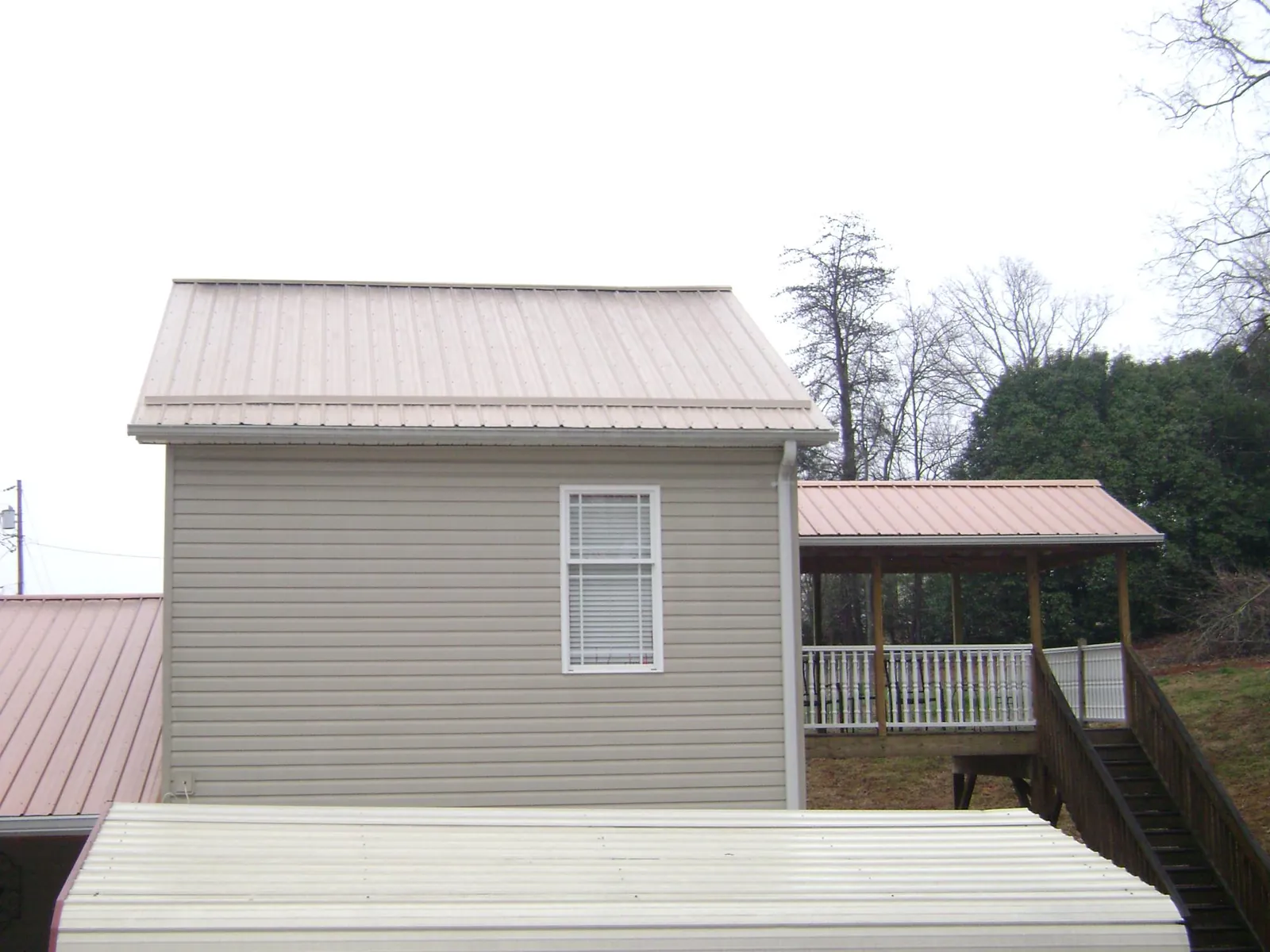 Tan metal roofs on a two story addition and attached porch, from a Roof Replacement job in Wickliffe