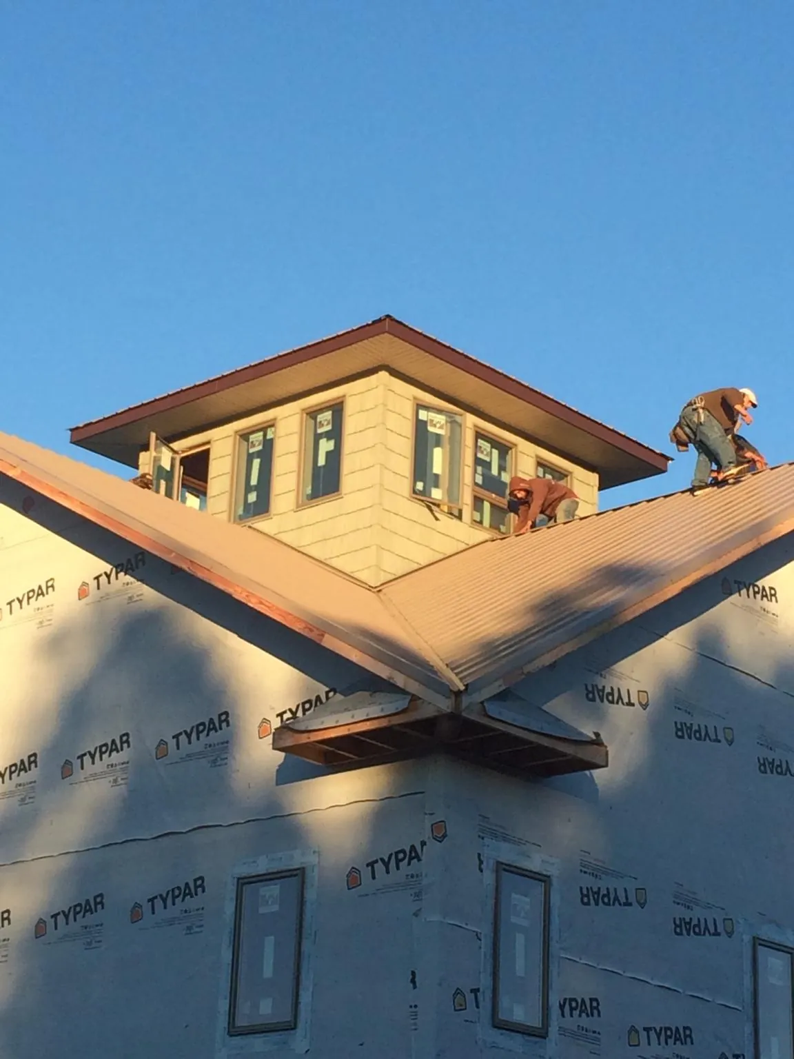 Roofers working around a rooftop cupola on a new metal roof at sunset — Roof Waterproofing in Wickliffe by Roofing Brothers